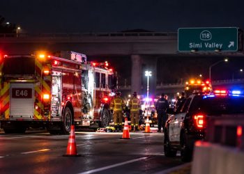 Nighttime emergency response on a Simi Valley freeway, with a fire engine, police vehicle, firefighters and traffic cones beneath an overpass.