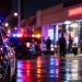 Nighttime police response outside a Bellflower smoke shop, with patrol vehicles, emergency lights and the storefront heavily blurred in the background.