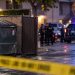 Police investigation scene near a Riverside apartment complex, with a dumpster enclosure and emergency vehicles blurred in the background.