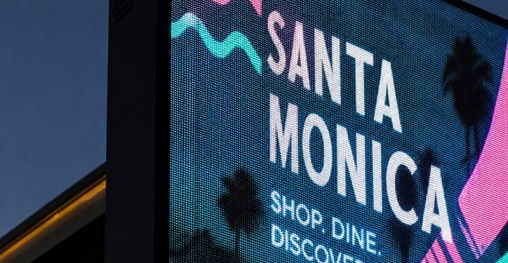 lose-up of an illuminated digital billboard at dusk, with the surrounding streetscape largely cropped out to emphasize the scale and brightness of the display.