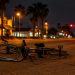 A damaged bicycle lying on its side in a lane of a wide suburban street in Montclair at night under street lamps, low stucco buildings behind.