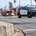 A rough concrete curb in sharp focus at Venice Boulevard and Catalina Street in Pico-Union, with a patrol SUV's lights flashing in the blurred background.