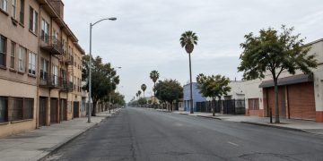 A street in South Los Angeles with older residential buildings and storefronts, photographed in neutral daylight, illustrating neighborhoods where homicides remain concentrated.