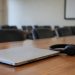 Close-up of a closed laptop, a headset and papers with illegible text on a conference table, illustrating the Los Angeles homeless services meeting.