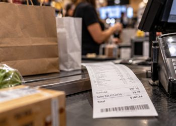 Close-up of a retail checkout counter with shopping bags and a sales receipt, illustrating the Los Angeles County sales tax increase taking effect Oct. 1.