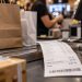 Close-up of a retail checkout counter with shopping bags and a sales receipt, illustrating the Los Angeles County sales tax increase taking effect Oct. 1.