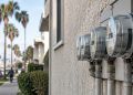 Close-up of a row of residential electric meters on a stucco wall in Los Angeles in neutral daylight, illustrating high LADWP summer bills.