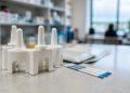 Close-up of naloxone nasal spray devices and drug test strips on a clinic counter in neutral daylight, illustrating the Los Angeles County opioid warning.