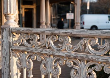 Close-up of ornate Victorian railings with weathered paint, with a blurred entrance behind, illustrating a historic nightclub venue closure.