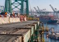 Close-up of the Vincent Thomas Bridge roadway and structural deck, with construction barriers and heavy port traffic blurred in the background.
