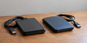 Close-up of two external hard drives side by side on a plain wooden table in soft indoor daylight, illustrating a Ventura County digital evidence case.