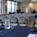 Community meeting room with a table of microphones in the foreground and rows of chairs blurred behind, illustrating a West Hollywood candidates forum.