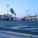 Early-morning view of a Santa Ana street with empty lanes and a curb in the foreground and emergency vehicle lights blurred in the distance.
