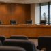 Empty city council dais with a curved wooden desk, microphones and high-backed chairs in a municipal chamber, illustrating West Hollywood's multi-partner ordinance.