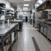 Empty commercial restaurant kitchen with stainless steel prep tables and a tiled floor under fluorescent light, illustrating restaurant health closures.