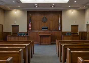 Empty courtroom with a wooden judge's bench, witness stand and rows of gallery seats under soft overhead light, illustrating the Superior Court judge race.