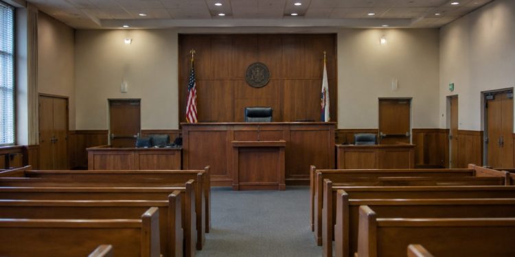 Empty courtroom with a wooden judge's bench, witness stand and rows of gallery seats under soft overhead light, illustrating the Superior Court judge race.