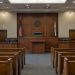 Empty courtroom with a wooden judge's bench, witness stand and rows of gallery seats under soft overhead light, illustrating the Superior Court judge race.