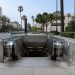 Empty escalator descending into a subway station entrance on Wilshire Boulevard in Los Angeles, with palm trees and mid-rise buildings in daylight.
