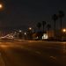 Empty multi-lane boulevard in the San Fernando Valley at night under street lamps, with low-rise buildings and palm trees along both sides.
