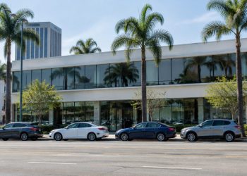 Exterior of a low-rise commercial building on a busy Los Angeles boulevard lined with palm trees in neutral daylight.