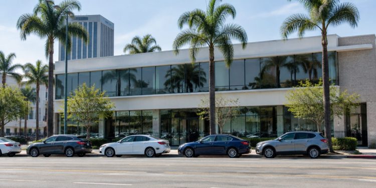 Exterior of a low-rise commercial building on a busy Los Angeles boulevard lined with palm trees in neutral daylight.