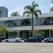 Exterior of a low-rise commercial building on a busy Los Angeles boulevard lined with palm trees in neutral daylight.