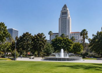 Grand Park in downtown Los Angeles with Los Angeles City Hall rising behind trees and empty paths in afternoon daylight.