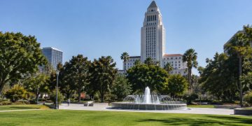 Grand Park in downtown Los Angeles with Los Angeles City Hall rising behind trees and empty paths in afternoon daylight.