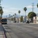Long-lens view down Vermont Avenue in South Los Angeles in morning daylight, with a city bus in the curb lane and palm trees along the street.