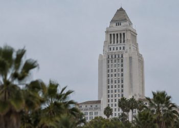 Los Angeles City Hall in neutral daylight, its tower sharp above softly blurred palm trees, illustrating a national city safety ranking.