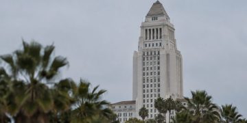 Los Angeles City Hall in neutral daylight, its tower sharp above softly blurred palm trees, illustrating a national city safety ranking.