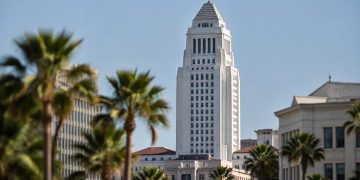 Los Angeles City Hall in neutral daylight, its tower sharp above softly blurred palm trees, illustrating the Los Angeles mayoral race.