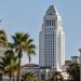 Los Angeles City Hall in neutral daylight, its tower sharp above softly blurred palm trees, illustrating the Los Angeles mayoral race.