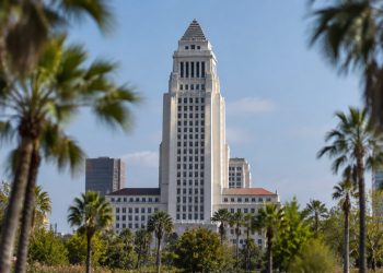 Los Angeles City Hall tower in daylight above softly blurred palm trees, illustrating the 2026 Los Angeles mayoral race.