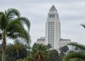 Los Angeles City Hall tower in neutral daylight above softly blurred palm trees, illustrating the Los Angeles mayoral runoff.