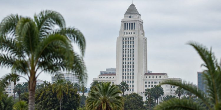 Los Angeles City Hall tower in neutral daylight above softly blurred palm trees, illustrating the Los Angeles mayoral runoff.