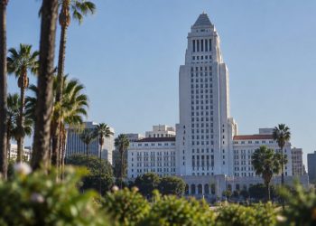 Los Angeles City Hall tower in neutral daylight above softly blurred palm trees, illustrating the Los Angeles mayoral runoff.