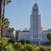Los Angeles City Hall tower in neutral daylight above softly blurred palm trees, illustrating the Los Angeles mayoral runoff.