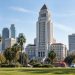 Los Angeles City Hall tower in neutral daylight, sharp above softly blurred palm trees, illustrating the 2026 Los Angeles mayoral race.