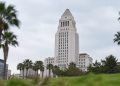 Los Angeles City Hall tower in neutral daylight, sharp above softly blurred palm trees in the foreground, illustrating the 2026 Los Angeles election.