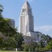 Los Angeles City Hall tower in neutral daylight, sharp above softly blurred trees, illustrating the council's public bank study vote.