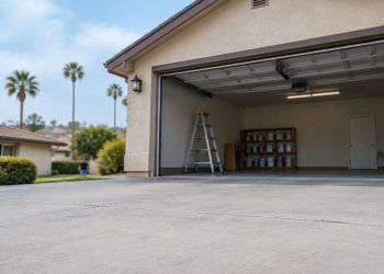 Open garage of a single-story stucco home with a bare concrete floor and a stepladder on a Granada Hills residential street in late-morning daylight.