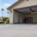 Open garage of a single-story stucco home with a bare concrete floor and a stepladder on a Granada Hills residential street in late-morning daylight.