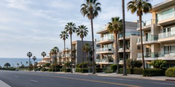 Palm-lined Ocean Avenue in Santa Monica in neutral daylight, with mid-rise beachside condominium buildings and balconies facing the Pacific.