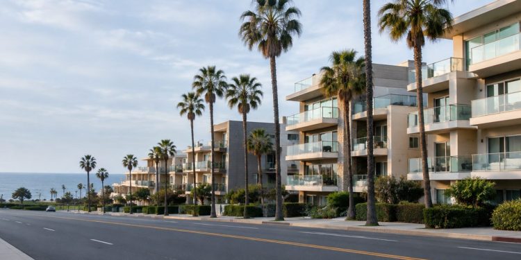 Palm-lined Ocean Avenue in Santa Monica in neutral daylight, with mid-rise beachside condominium buildings and balconies facing the Pacific.