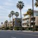 Palm-lined Ocean Avenue in Santa Monica in neutral daylight, with mid-rise beachside condominium buildings and balconies facing the Pacific.