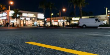 Parking lot of a commercial market in West Hollywood at night, with a yellow parking stripe in sharp focus and storefronts blurred along Santa Monica Boulevard.