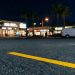 Parking lot of a commercial market in West Hollywood at night, with a yellow parking stripe in sharp focus and storefronts blurred along Santa Monica Boulevard.