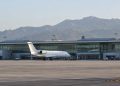 Passenger jet parked on the apron outside a modern airport terminal with a long glass facade in Burbank in soft early-morning daylight.